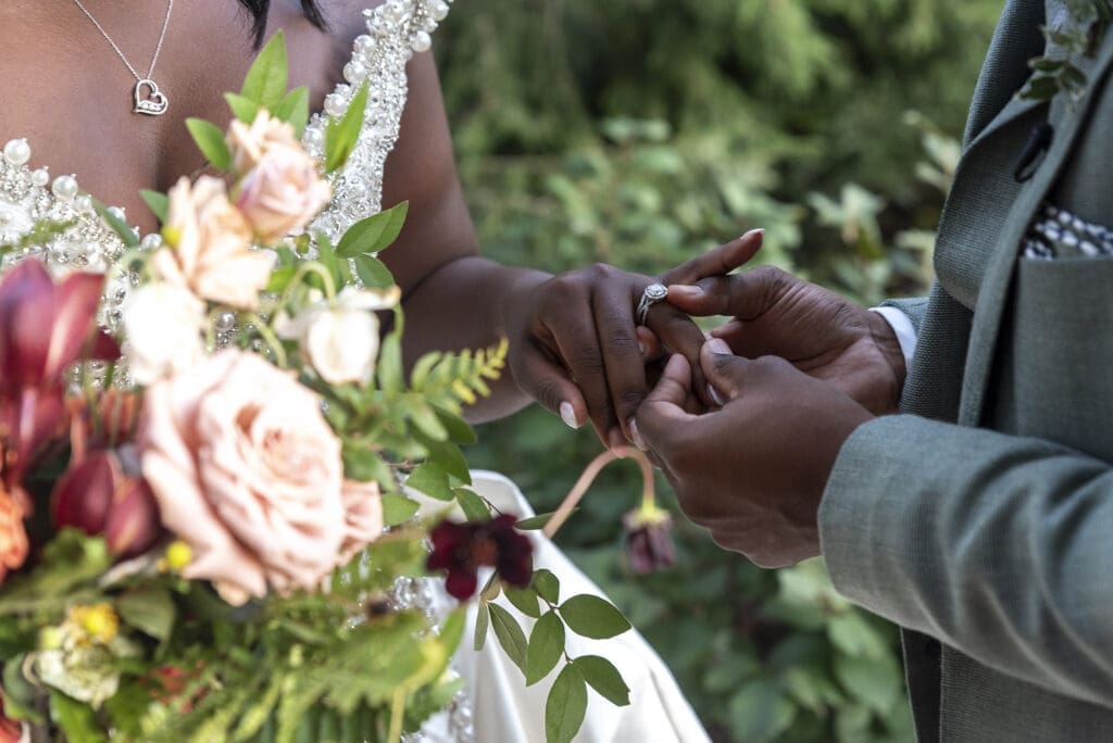 close up of bride holding bouquet in one hand then holding brooms hand with the other