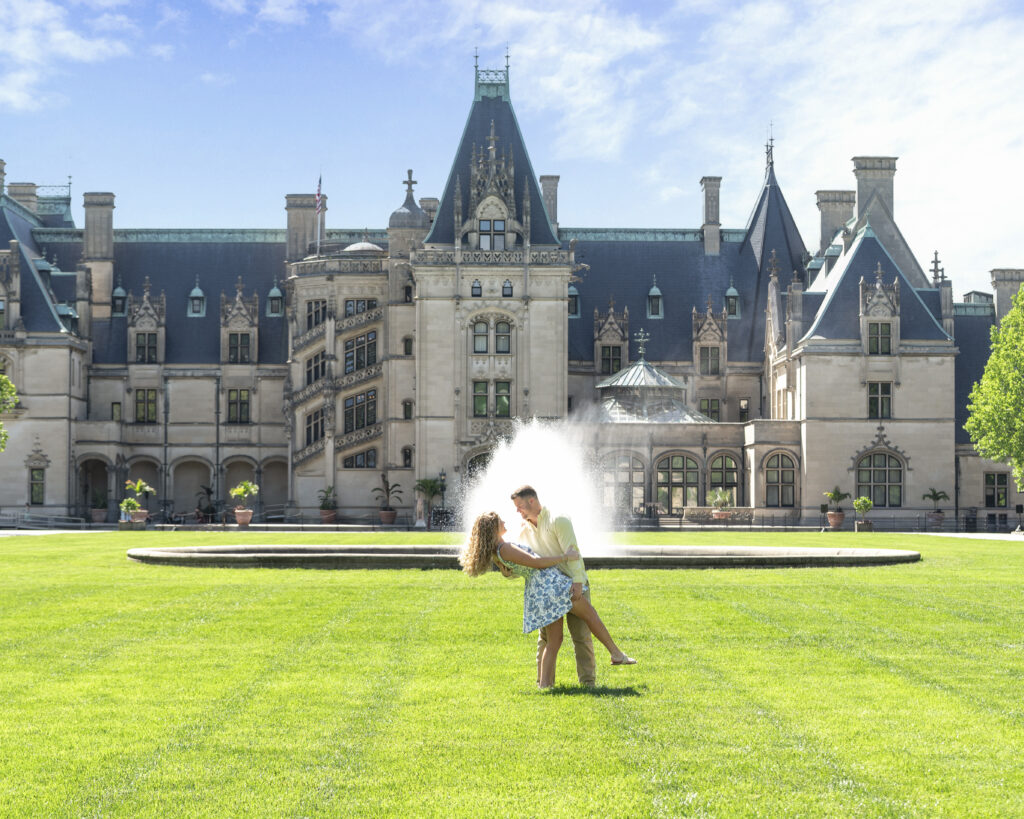 man lean dipping woman on the front lawn centered by the water fountain and the Biltmore Estate in background