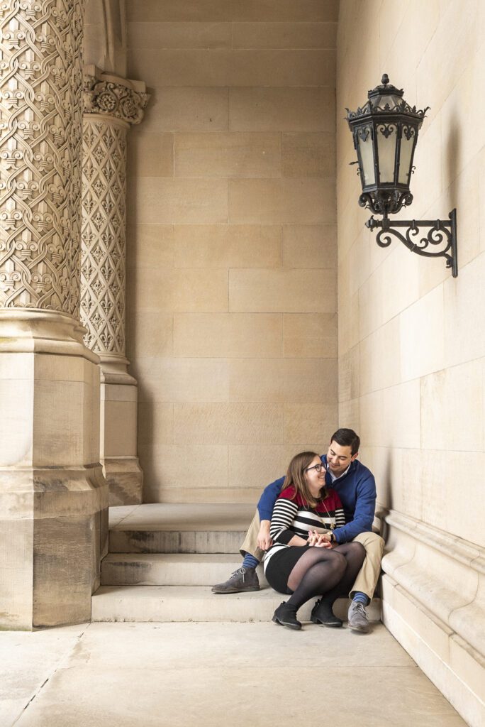 newly engaged couple sitting on stairs looking at each other surrounded by Biltmore Estate Architecture