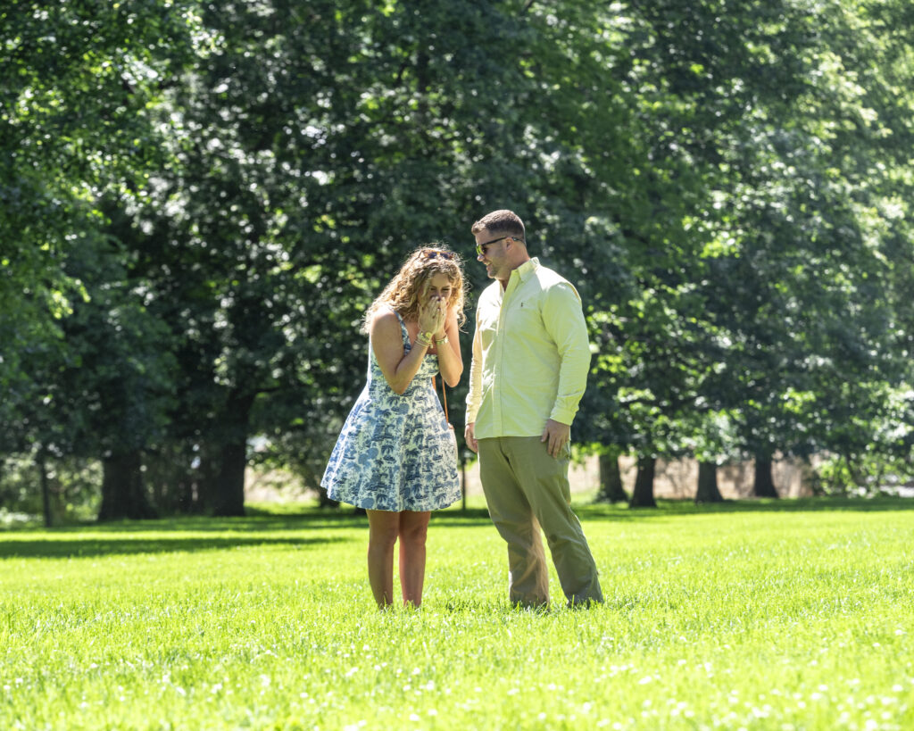 Biltmore estate proposal, man looking at his fiance just after she said "yes". she is leaned over with hands on face looking happily surprised at the top of Diana Lawn