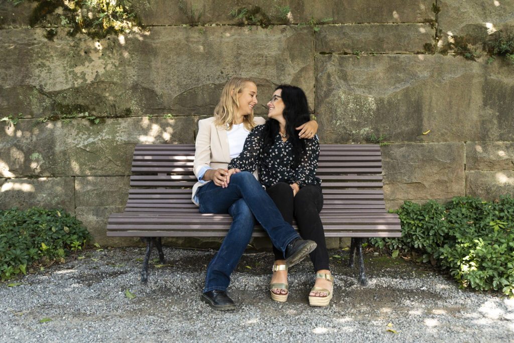 lesbian couple sitting on bench under wisteria at Biltmore Estate