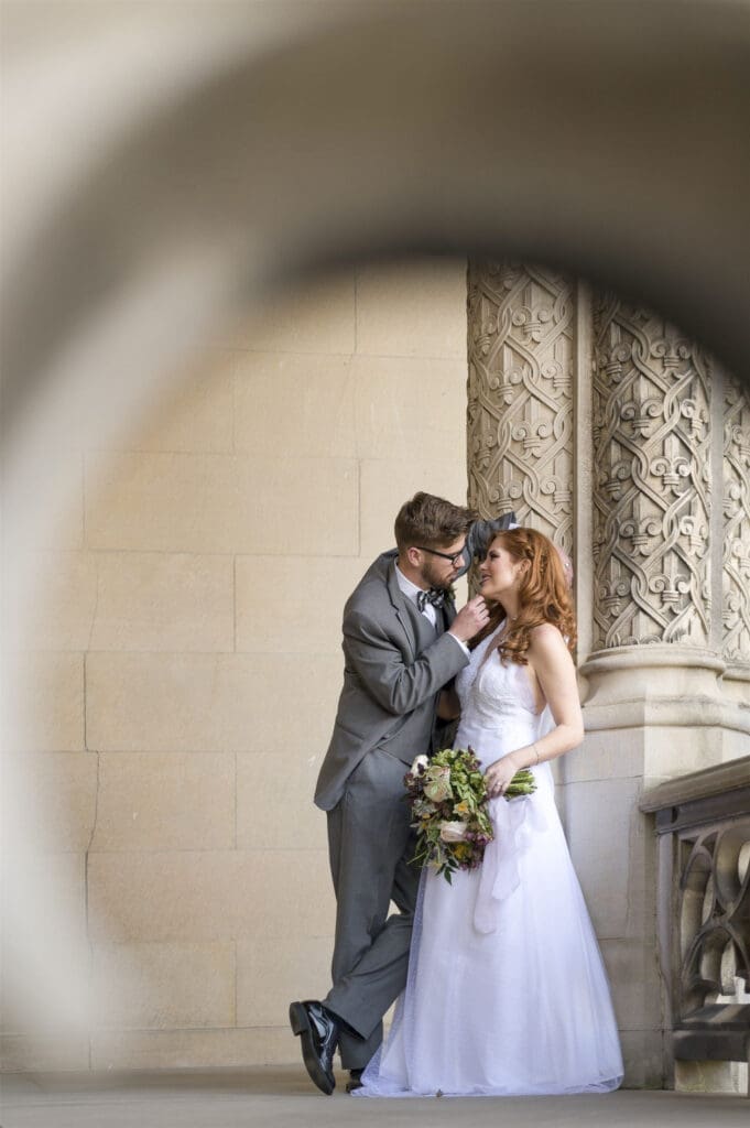 wide image of Bride and groom kissing leaning against the architecture of Biltmore Estate 