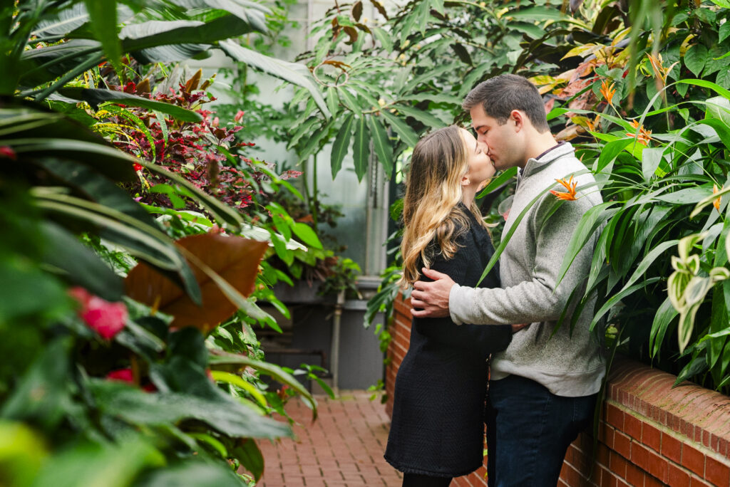 engaged couple embracing and kissing in the Biltmore Estate conservatory