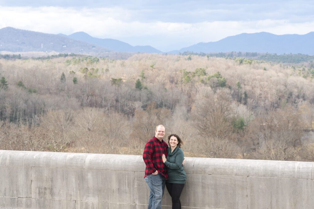 newly engaged couple standing on the south terrace looking at camera with blue ridge mountains in the background