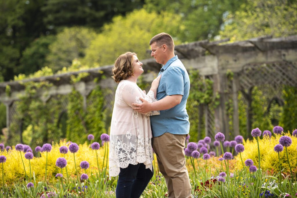 engaged couple standing in Biltmore flower garden looking at each other and embracing.