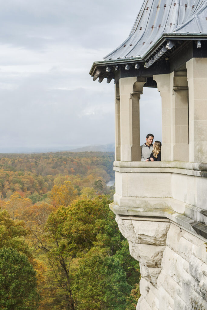 Couple standing in the tea house on Biltmore's south terrace with the fall mountain color and french broad river in the background