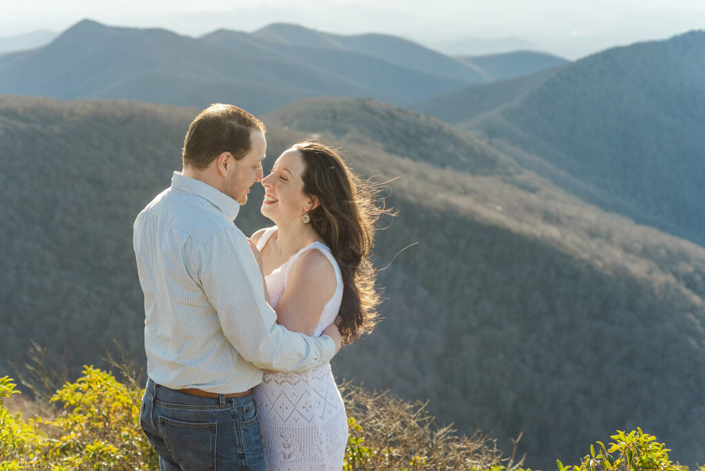 Couple embracing at the top of Craggy Pinnacle.with the blue ridge mountains in the background