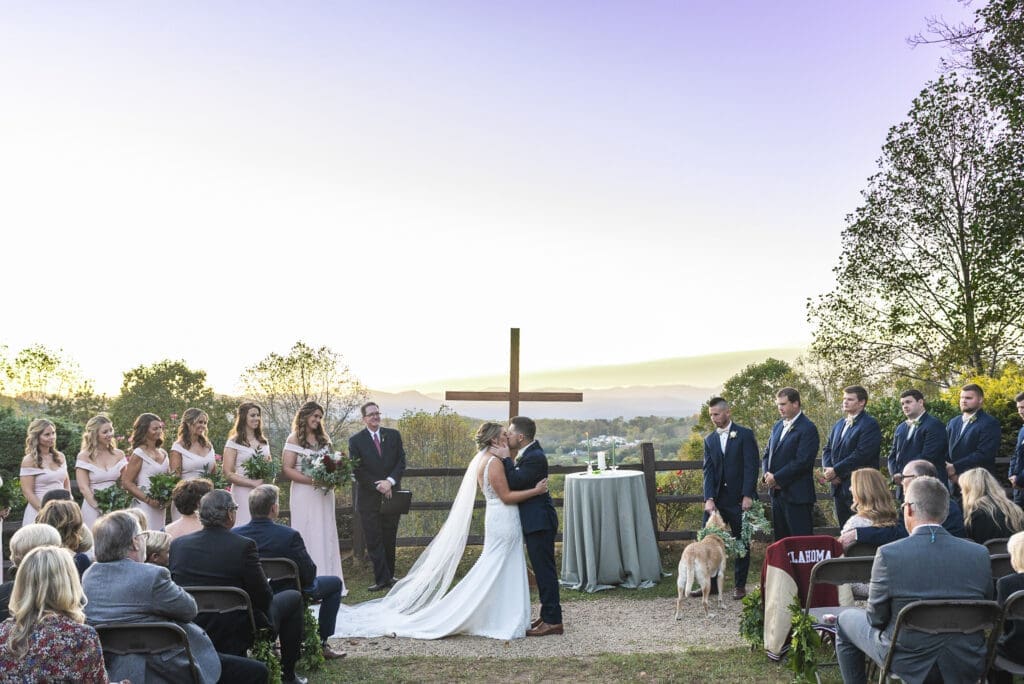 bride and groom first kiss during outdoor ceremony with mountains in background at Crest center and pavilion