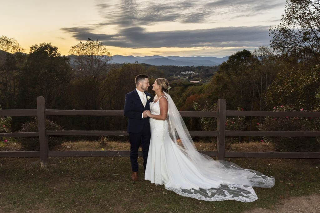 bride and groom holding hands looking at each other during sunset at overlooking the mountains at Crest center and pavilion