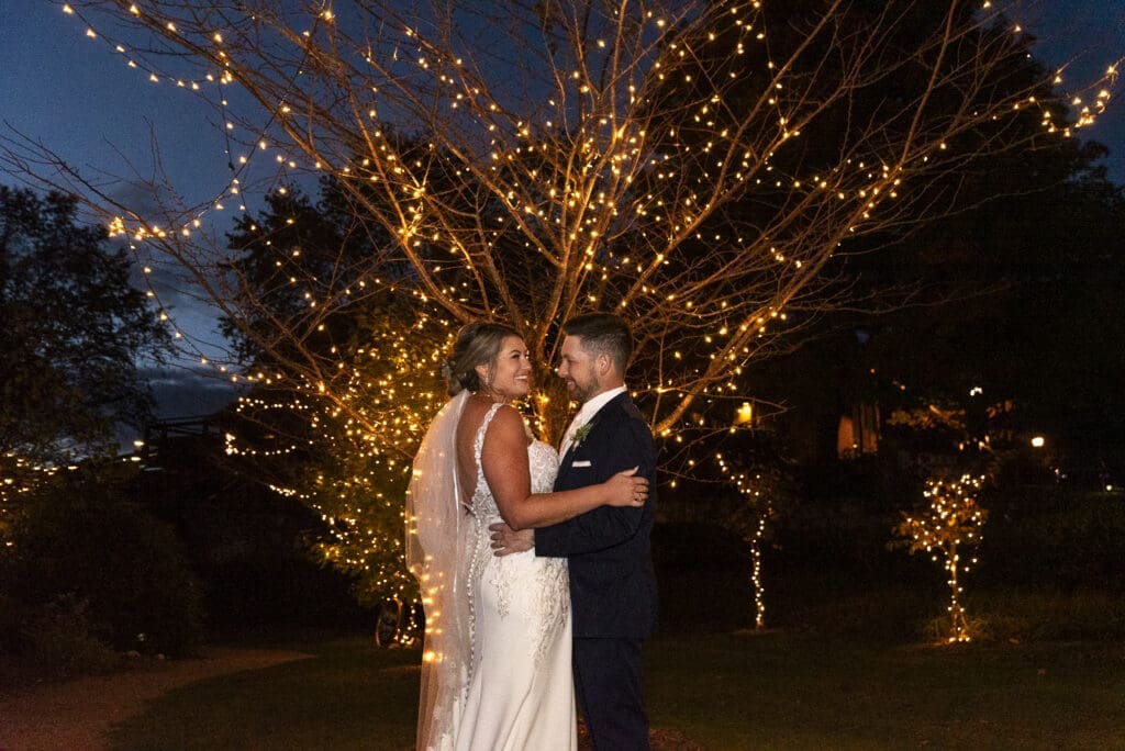 bride and groom evening pictures in front of light tree at crest center and pavilion asheville