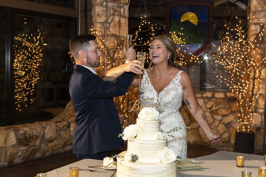 bride and good smiling as they champagne toast after cake cutting during reception at crest center asheville