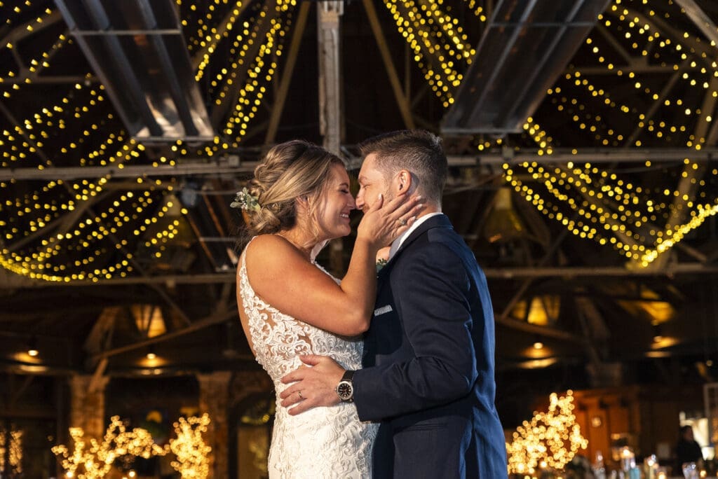 bride and groom slow dancing. bride smiling as she pulls grooms face toward hers during their first dance at Crest Center in Asheville.