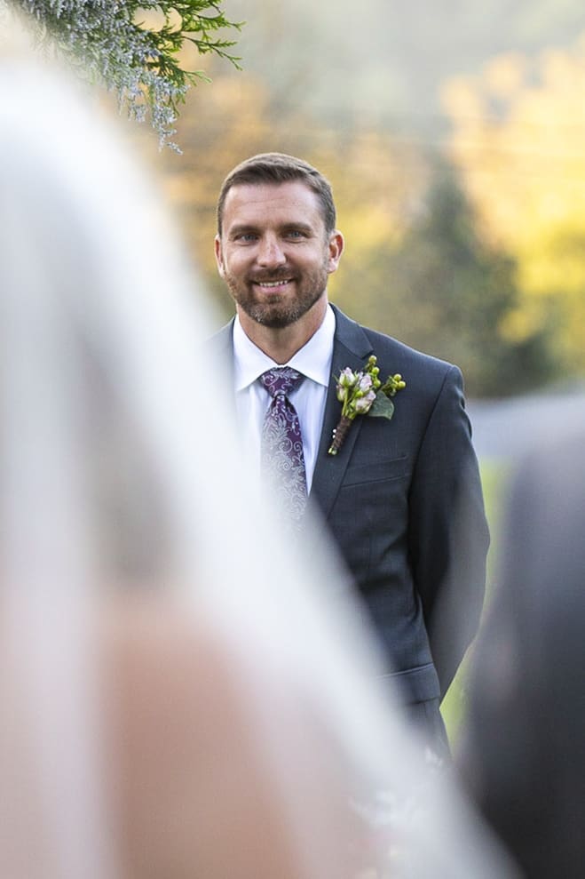 close up of groom as bride walks down asile at fields of blackberry cove