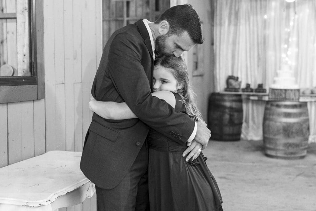 Father embracing young daughter at his wedding reception