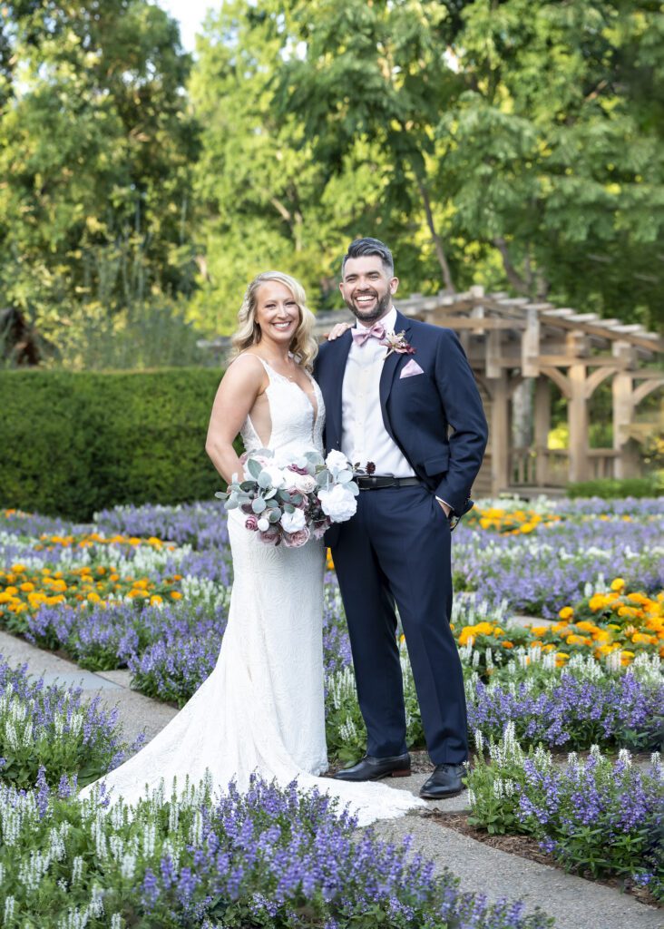 Bride and groom in the butterfly garden at NC arboretum holding hands looking at camera
