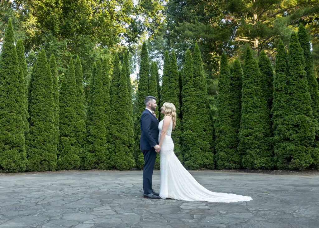 Bride and groom at NC arboretum holding hands looking at each other in Amphitheater