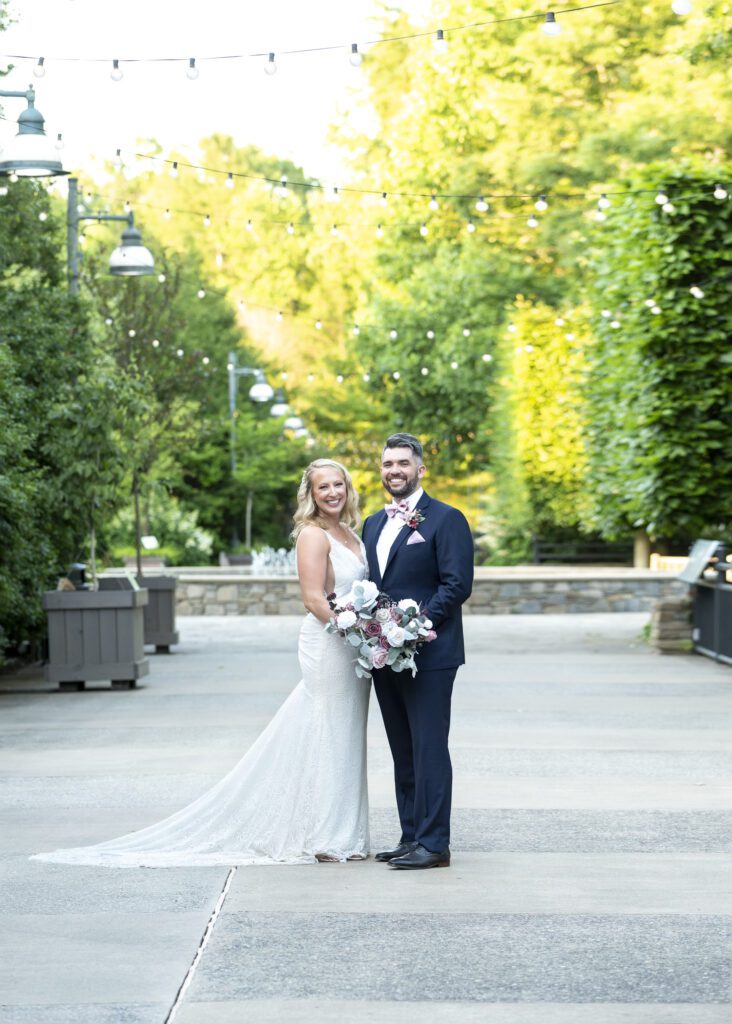 Bride and groom at NC arboretum holding hands looking at camera