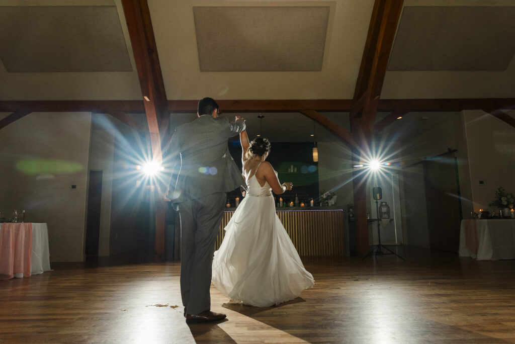 wide of bride and groom last dance with flashing lights in the back at Weaver House wedding venue