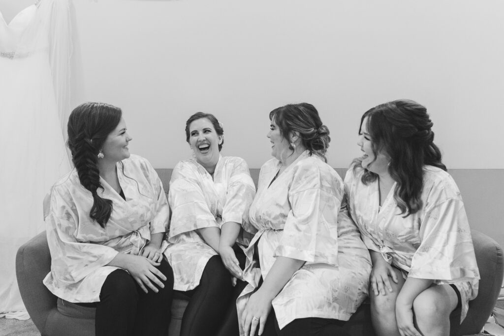 bride and bridesmaids in matching robes laughing before ceremony at Weaver House wedding venue