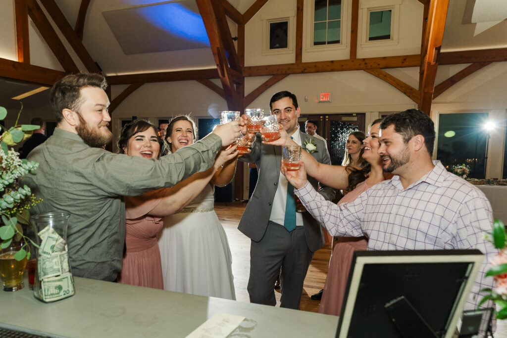 wide of bride, groom, and their friends holding glasses up to cheers at Weaver House wedding venue