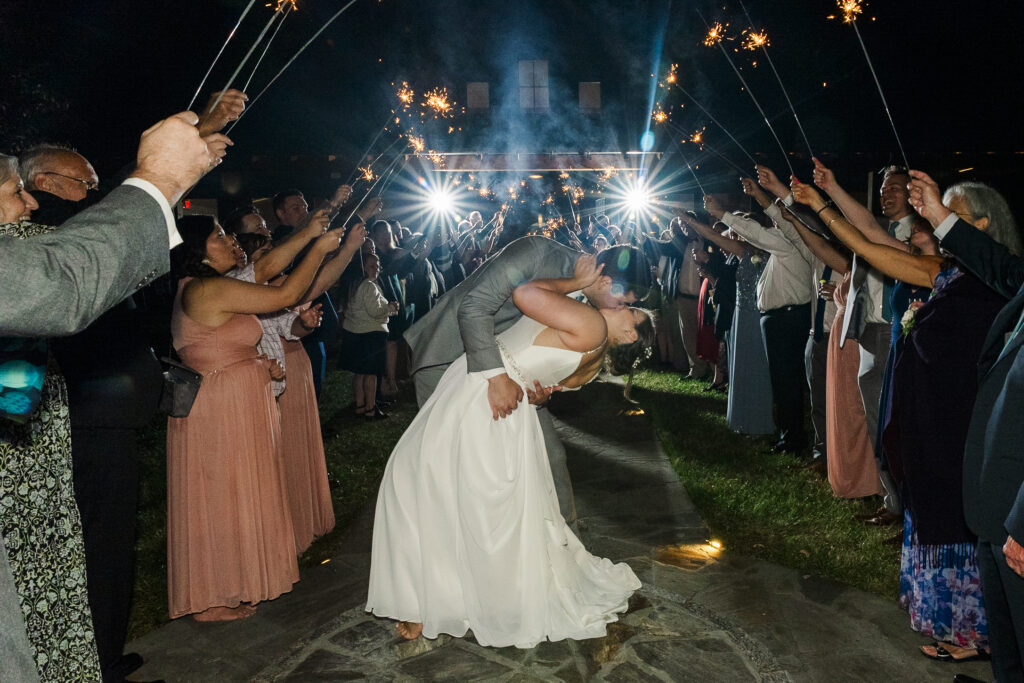 groom dipping bride for a kiss at the end of the sparkler exit at at Weaver House wedding venue