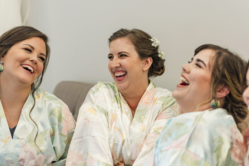 close up of bride and bridesmaids in matching robes laughing before ceremony at Weaver House wedding venue