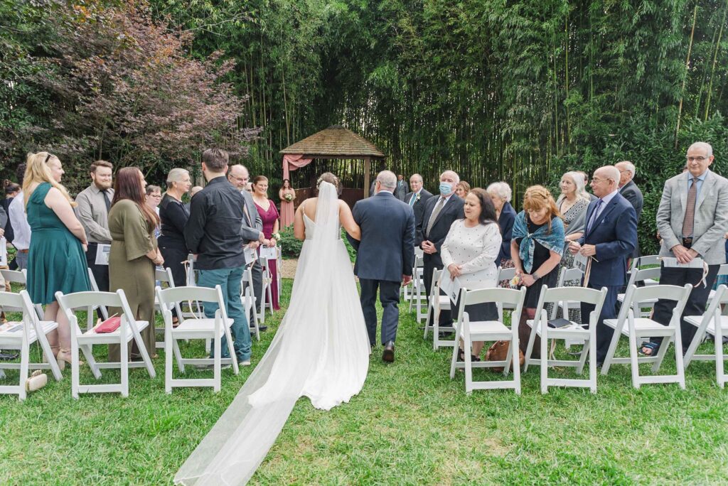 Bride walking down the ceremony aisle with her father as gusts look on at Weaver House wedding venue