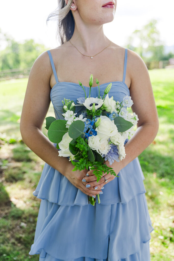 bridesmaid holding bouquet with wind blowing her hair and image is cropped below nose and above knee