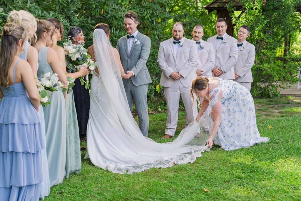 maid of honor fixing brides train during ceremony at The Farm A Gathering Place Asheville Candler Wedding Venue