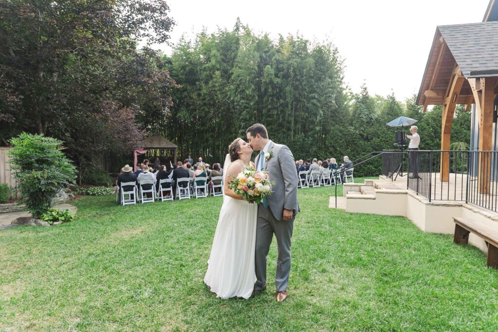 bride and groom at the end of the aisle kissing after ceremony at Weaver House wedding venue