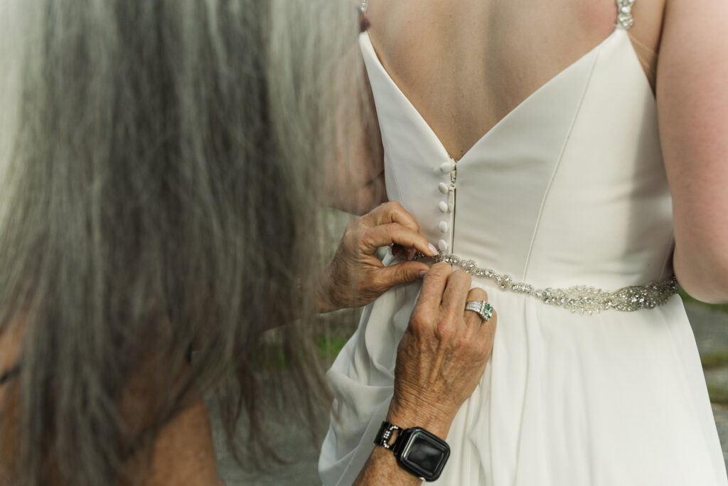 close up detail of bride's mother buttoning her dress