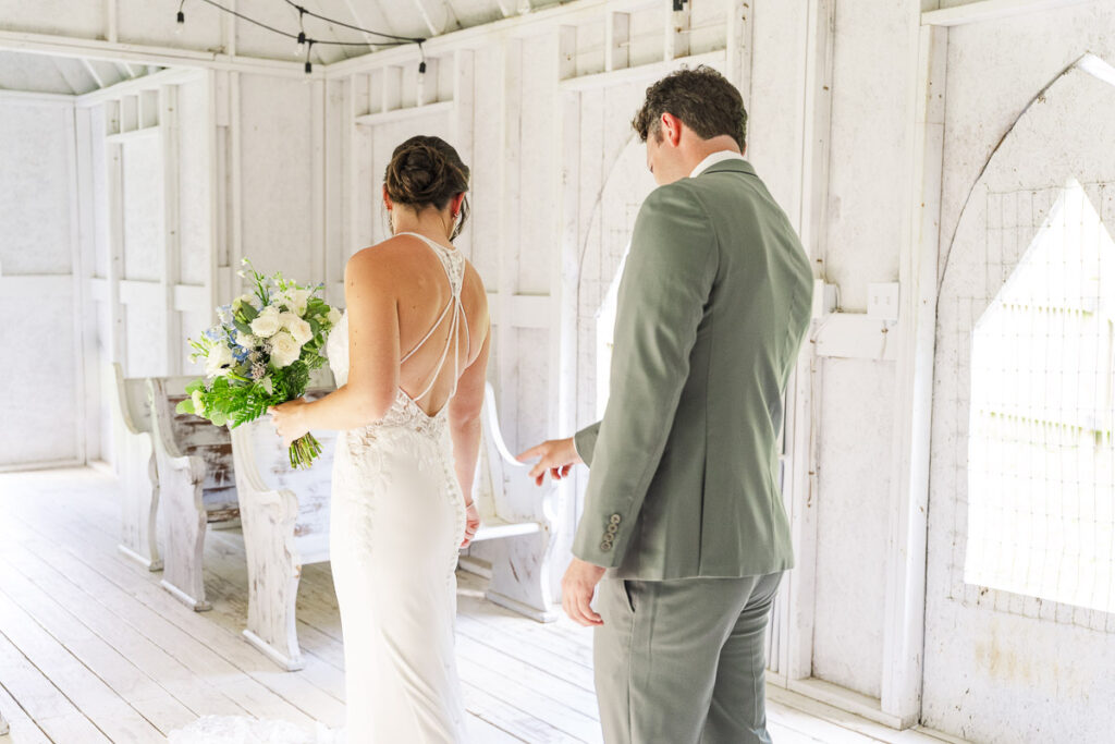 groom looking at the back of bride's dress during first look