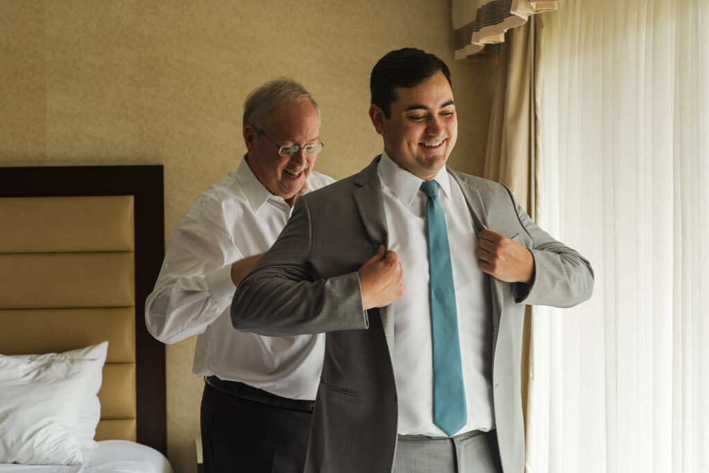 groom's father helping him put his suit jacket on